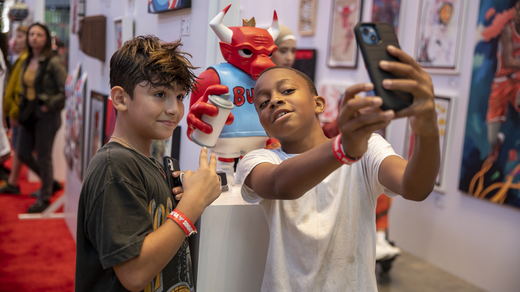 Two boys pose in front of a Benny the Bull sculpture at Bulls Fest 