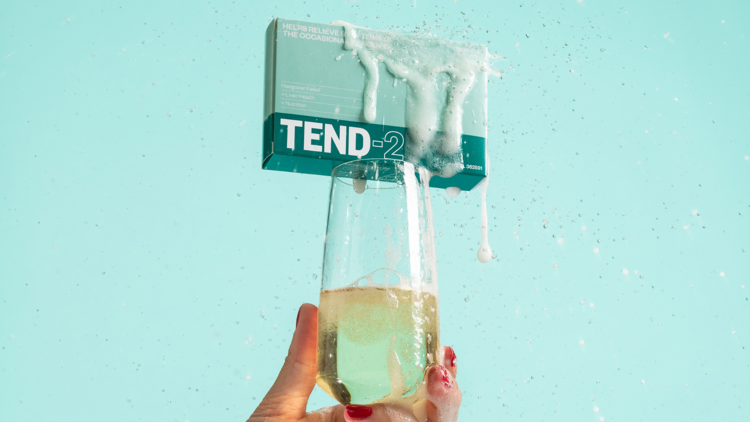 A box of hangover relief capsules resting atop a glass of sparkling wine.