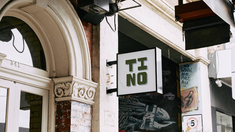 The exterior of Tino, noted by a white marquee with green lettering reading Tino.