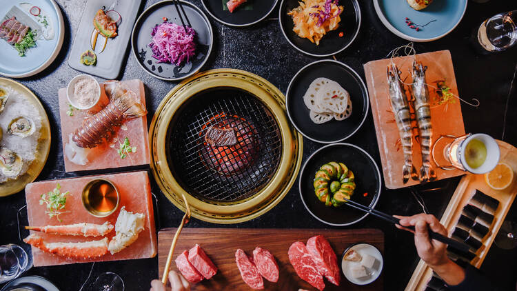 A variety of dishes spread out on a table with a grill.