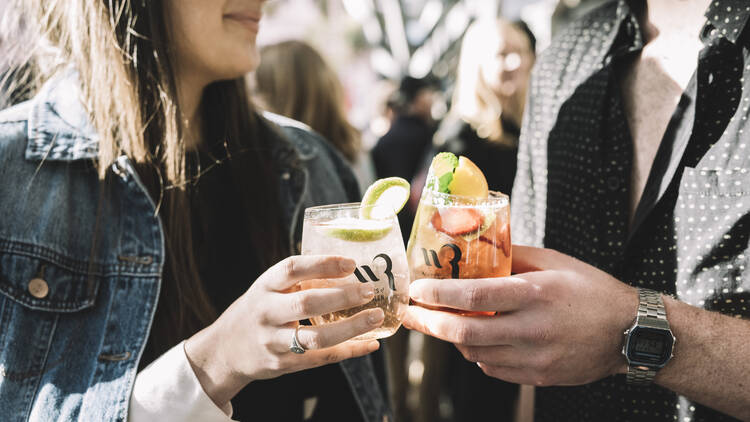 Two people cheersing with glasses of wine cocktails.