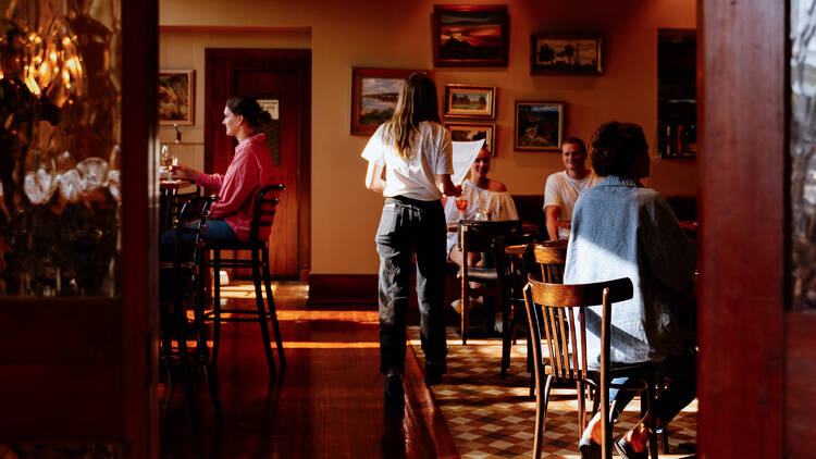 A waitress bringing menus to a table of diners in a pub.