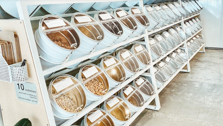 A shelf at a bulk-buy food store stocked with bulk nuts, seeds and more.