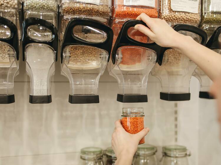 A person pulling the lever on a dispenser filled with lentils.