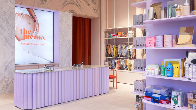A pastel purple cashier's stand flanked by shelves offering boutique baby goods.