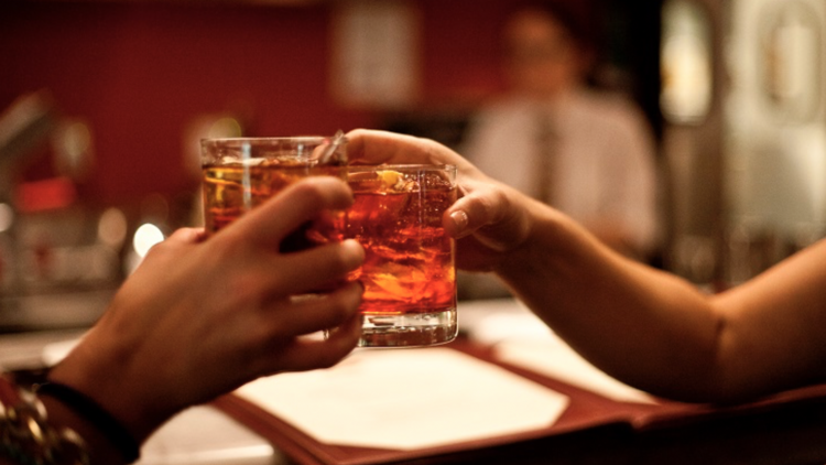 Two people cheers with Negronis.