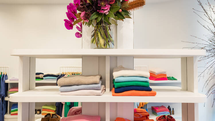 White shelves filled with a variety of colourful cashmere jumpers.