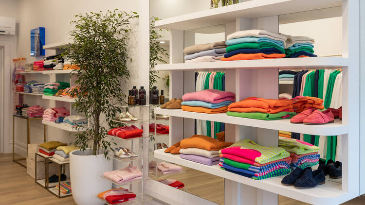 White shelves lined with a variety of colourful cashmere sweaters.