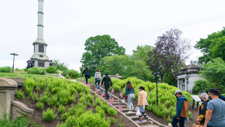 A group of people walks past grave markers.