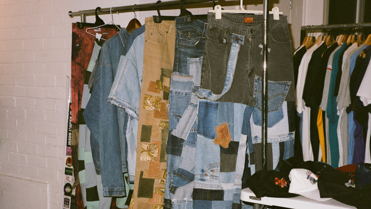A clothes rack with several pieces of vintage garments, mostly denim.