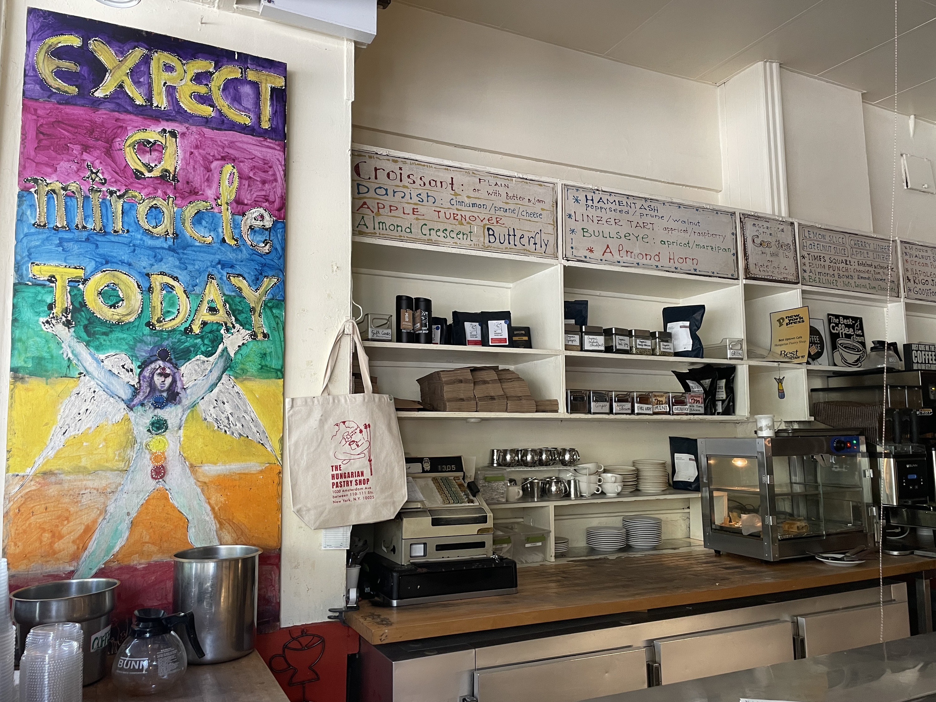 The interior of the Hungarian Pastry Shop with its menu visible and a sign reading "expect a miracle today."