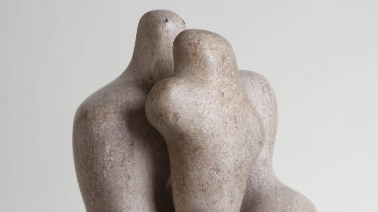 A stone sculpture of an abstract shape with a smaller abstract shape sitting on top of it that resembles a mother and a child.