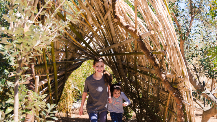 Kids run through a woven archway in the Ian Potter garden playground 