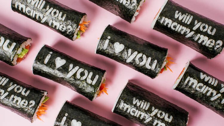 Sushi hand rolls with various messages etched into the seaweed including I love you