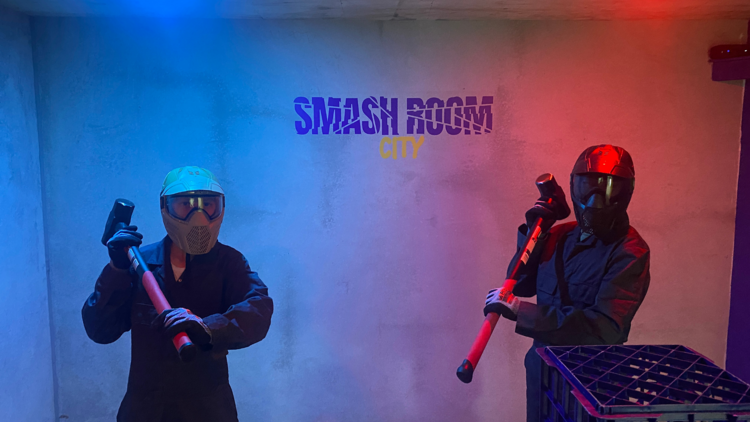 Two people pose with sledgehammers at Smash Room City 