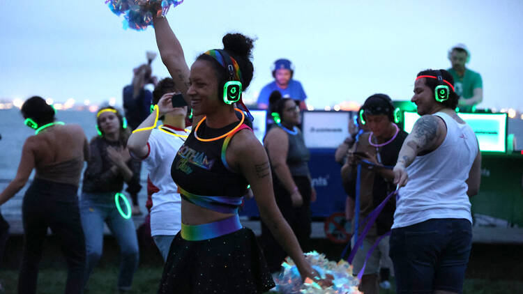 A woman holds pom-poms while dancing at a silent disco.