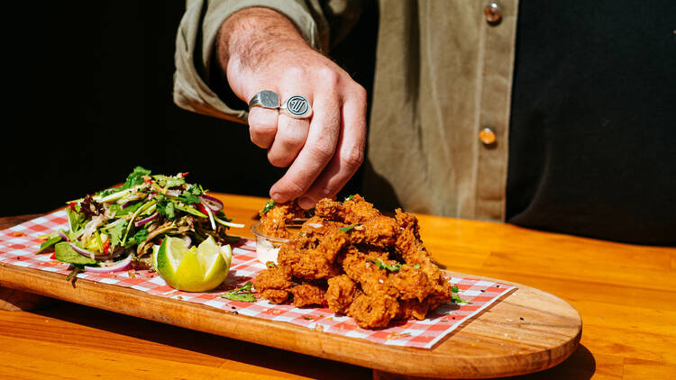 A photo of hand reaching out to grab some chicken wings