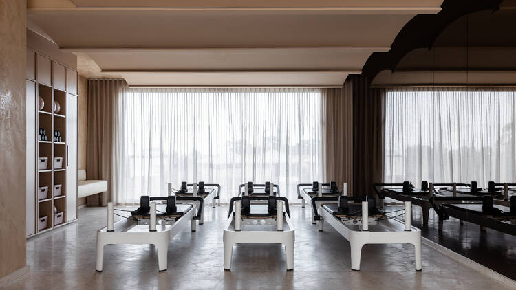 A light-filled room with a floor-to-ceiling mirror and reformer pilates machines