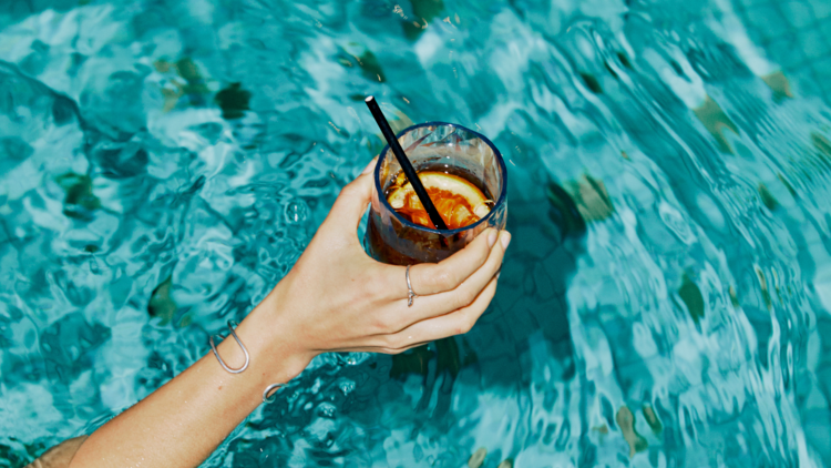 A person holding a mocktail in a pool.