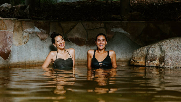 Two women bathing in an outdoor hot springs.