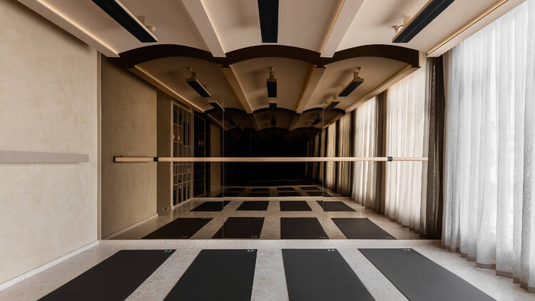 A light, modern room with a floor-to-ceiling mirror and four pilates mats.