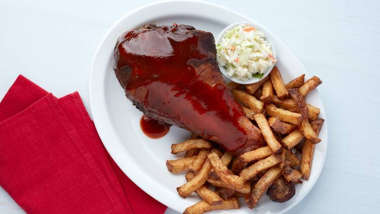 A smoked turkey leg with fries and coleslaw.