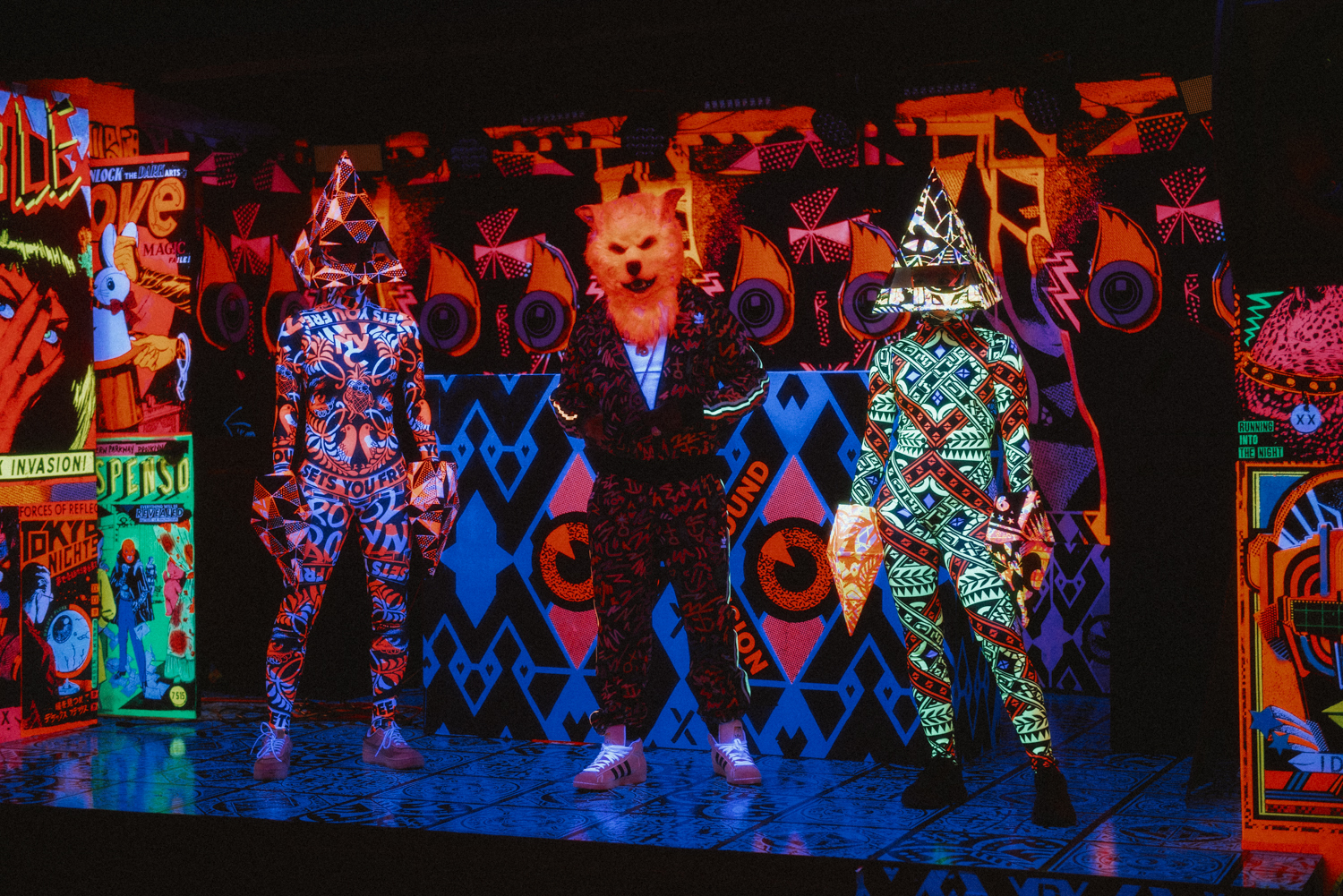 A video projection showing three people, one wearing a cat mask.