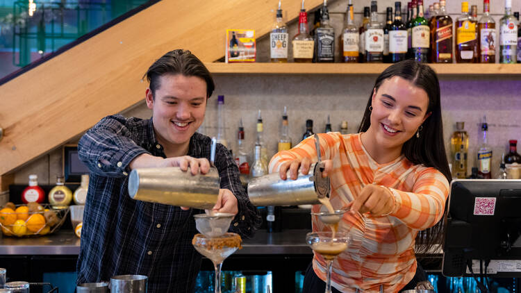 Two bartenders are making cocktails