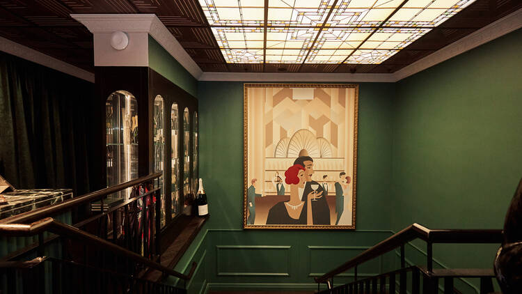 A large painting hangs on the dark green walls above the staircase