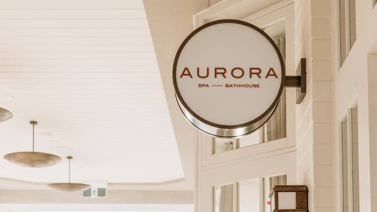 A white circular sign on a building that says 'Aurora Spa – Bathhouse'