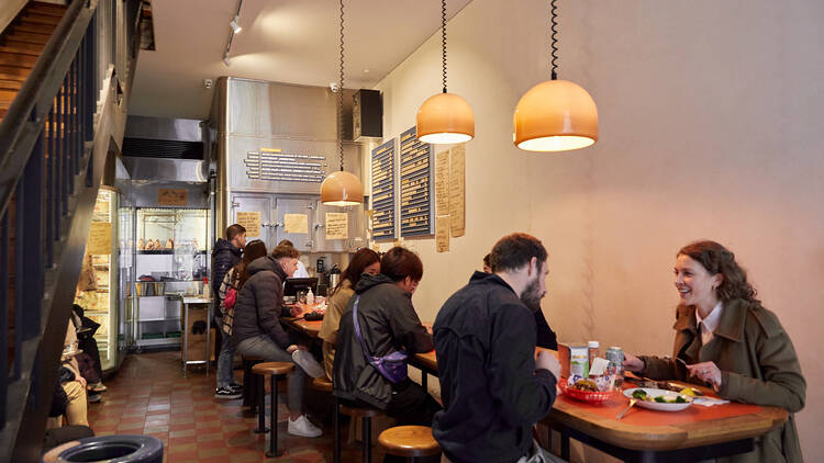 People sit at tables inside Butcher's Diner with tiled floors and low hung dim lights