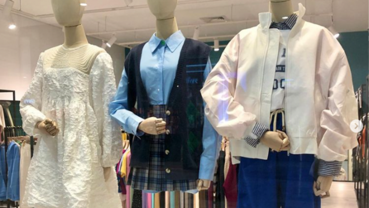 Three mannequins wearing (L-R) a white dress, a blue school uniform and a bomber jacket.