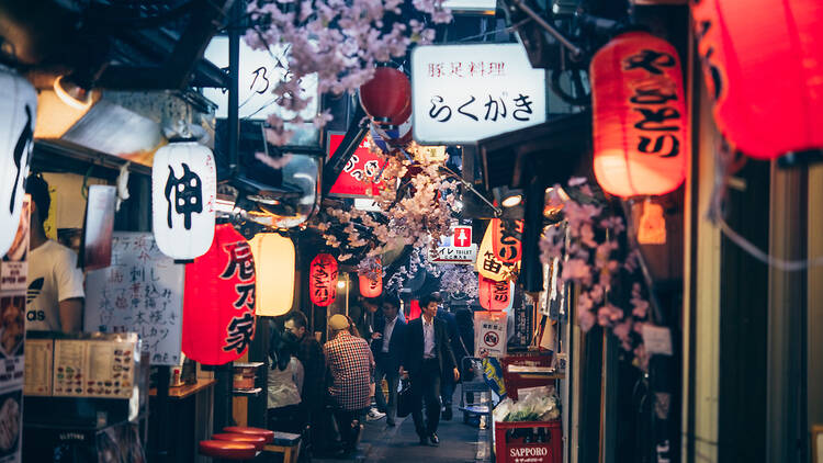 A man walking through a lantern-lit street of Japan.