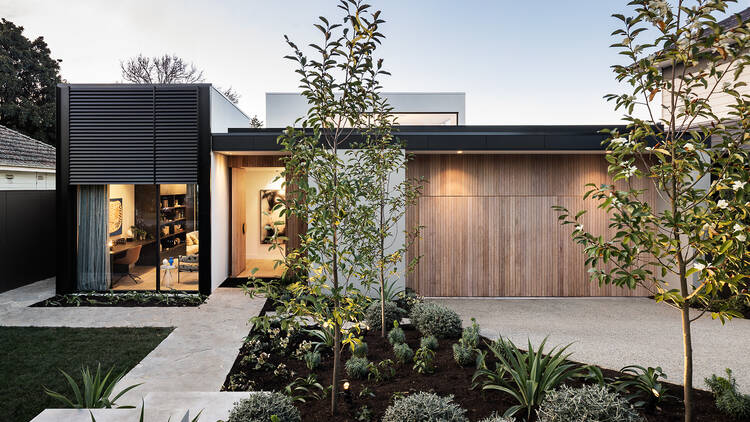 The exterior of a new and modern home with trees and plants in the garden