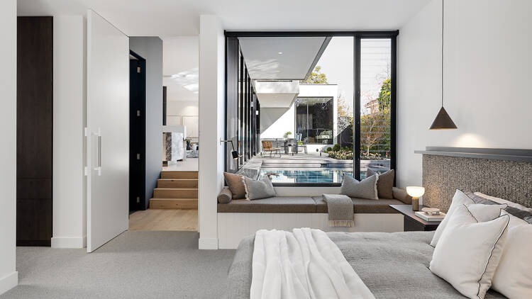 A bedroom with a big glass window overlooking the pool