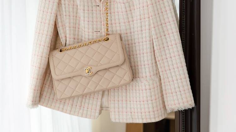 A cream Chanel bag against a cream jacket