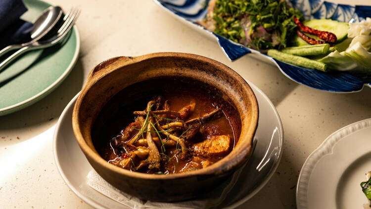 A claypot dish filled different vegetables on a table with other dishes in the background