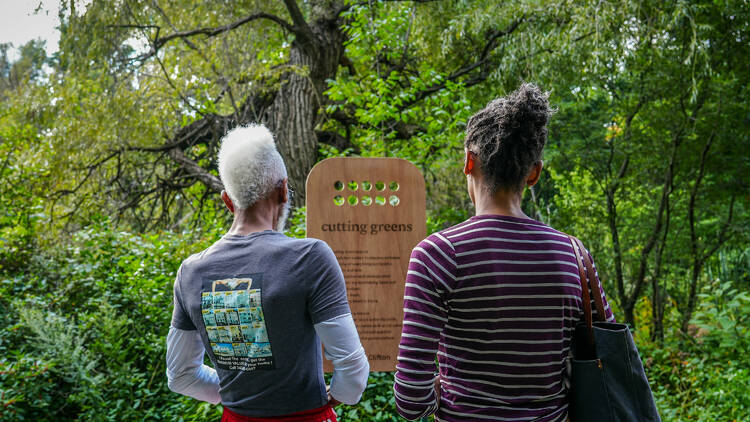 Two people read the poetry artwork at New York Botanical Garden.
