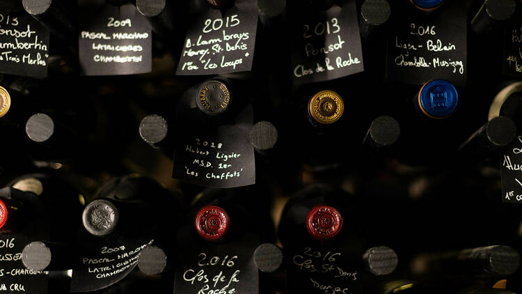 The wine cellar with black signs with white writing labelling the bottles 