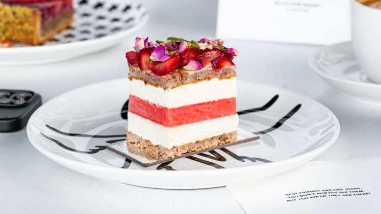 The strawberry and watermelon layered cake sits on a white plate