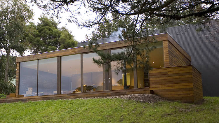 A large wooden room with glass doors at the front houses the restaurant on top of a grassy hill