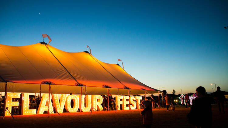 A large outdoor tent with lettered signs reading 'Flavour Fest'