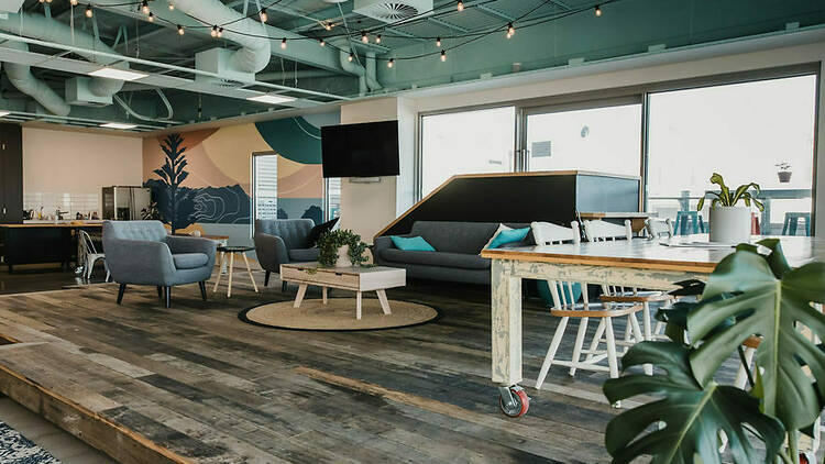A co-working space featuring shared desks, couches and a full kitchenette.