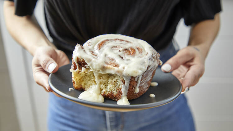 A person holding a cinnamon roll.