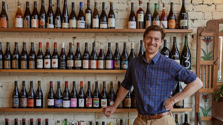 A bar owner with a wall of wine bottles