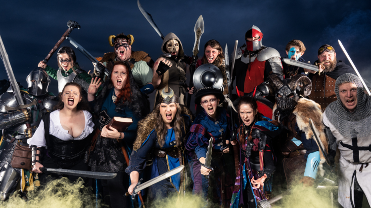 A group of people in costume holding swords shout at the camera