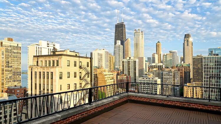 A rooftop terrace shows views of the Chicago skyline with a blue sky overhead