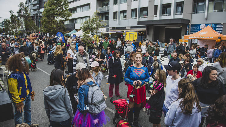 A crowd of people and dogs on a street all in costume.