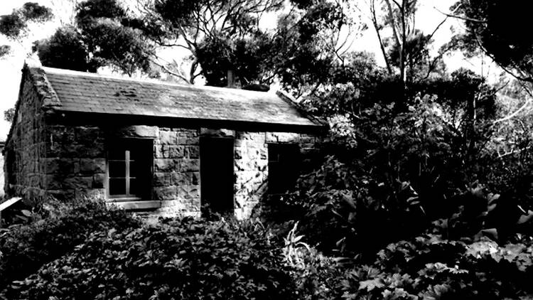 A black and white photo of a brick cottage.