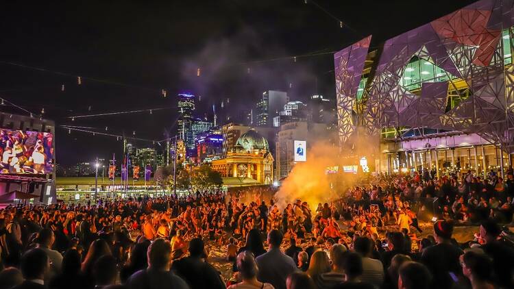 A crowd gathered in Fed Square in Melbourne at night